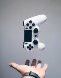 A person's hand holding a PlayStation controller.